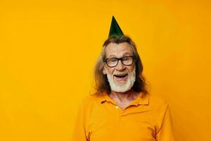 retrato do feliz Senior homem dentro uma amarelo camiseta com uma boné em dele cabeça Diversão amarelo fundo foto