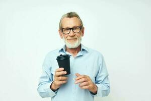 retrato do feliz Senior homem com uma Preto vidro dentro dele mãos uma beber isolado fundo foto