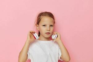 retrato do feliz sorridente criança menina dentro uma branco camiseta com fones de ouvido infância inalterado foto