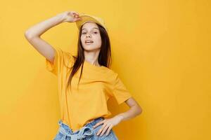 otimista jovem mulher posando dentro uma amarelo camiseta e boné amarelo fundo foto