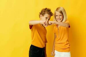 fofa à moda crianças dentro amarelo Camisetas em pé lado de lado infância emoções isolado fundo foto