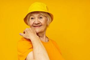 retrato do a velho amigáveis mulher feliz estilo de vida dentro uma amarelo cocar amarelo fundo foto