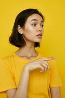 jovem mulher dentro amarelo camiseta posando moda amarelo fundo foto