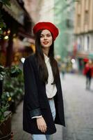 mulher sorrir moda modelo anda em em a rua dentro a cidade Centro entre a multidão dentro uma Jaqueta e vermelho boina e jeans, cinematográfico francês moda estilo roupas, viagem para Istambul Primavera foto