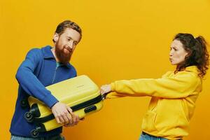 mulher e homem sorridente, malas dentro mão com amarelo e vermelho mala de viagem sorridente alegremente e torto, amarelo fundo, indo em uma viagem, família período de férias viagem, recém-casados. foto