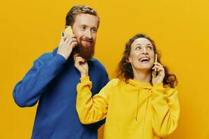 mulher e homem alegre casal com telefones dentro mão falando em célula telefone torto sorrir alegre, em amarelo fundo. a conceito do real família relacionamentos, falando em a telefone, trabalhos on-line. foto