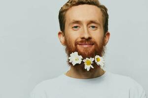 retrato do uma engraçado homem dentro uma branco camiseta com flores margaridas dentro dele barba em uma branco isolado fundo, cópia de lugar. feriado conceito e Parabéns. foto