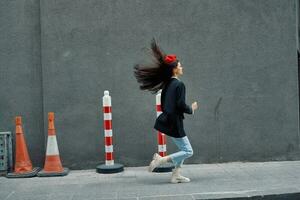 moda mulher corrida baixa a rua dentro frente do a cidade turista dentro à moda roupas com vermelho lábios e vermelho boina, viagem, cinematográfico cor, retro vintage estilo. foto