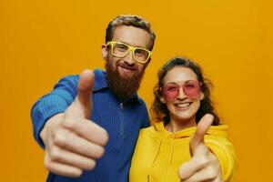 homem e mulher casal sorridente alegremente e torto com copos, em amarelo fundo, símbolos sinais e mão gestos, família atirar, recém-casados. foto