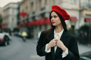 moda mulher retrato beleza em pé em a rua dentro frente do a cidade dentro à moda roupas com vermelho lábios e vermelho boina, viagem, cinematográfico cor, retro vintage estilo, urbano moda estilo de vida. foto