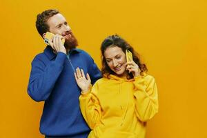 homem e mulher casal sorridente alegremente com telefone dentro mão social meios de comunicação vendo fotos e vídeos, em amarelo fundo, símbolos sinais e mão gestos, família freelancers.