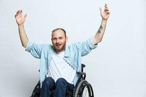 uma homem dentro uma cadeira de rodas parece às a Câmera raiva e agressão, com tatuagens em dele braços senta em uma cinzento estúdio fundo, saúde conceito homem com deficiências foto