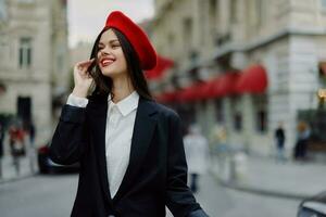 moda mulher retrato sorrir com dentes em pé em a rua dentro a cidade fundo dentro à moda roupas vermelho lábios e vermelho boina, viagem, cinematográfico cor, retro vintage estilo, urbano moda estilo de vida. foto