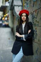 moda mulher retrato caminhando turista dentro à moda roupas com vermelho lábios caminhando baixa uma limitar cidade rua, viagem, cinematográfico cor, retro vintage estilo, dramático contra uma parede com grafite. foto