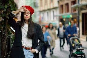 mulher moda modelo anda em em a rua dentro a cidade Centro entre a multidão dentro uma Jaqueta e vermelho boina e jeans, cinematográfico francês moda estilo roupas, viagem para Istambul foto