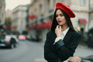 moda mulher retrato em pé em a rua dentro frente do a cidade dentro à moda roupas com vermelho lábios e vermelho boina, viagem, cinematográfico cor, retro vintage estilo, urbano moda estilo de vida. foto