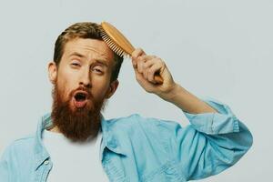 retrato do uma homem com uma massagem pente dentro dele mãos, pentear dele cabelo e barba, cabelo perda problema foto