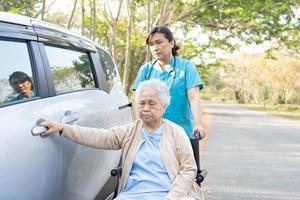 ajuda e suporte mulher idosa asiática ou paciente idosa sentada na cadeira de rodas prepare-se para chegar ao carro foto