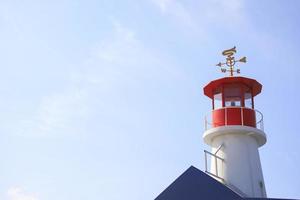 farol vermelho e branco com céu azul no verão foto