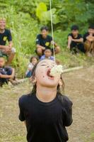 agosto 17, tasikmalaya, oeste Java, Indonésia - crianças levando parte dentro uma biscoito comendo concorrência, que é uma Formato do a comemorar indonésio independência dia em agosto 17 foto