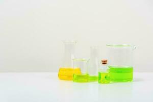 alguns teste tubo em a branco mesa com copos, frascos, e teste tubos preenchidas com colorida líquidos foto