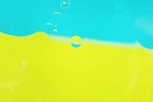 uma macro bonita e colorida de bolhas de óleo na água com duas cores de fundo de alto contraste, azul e amarelo foto