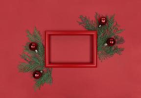 moldura vermelha, galhos de árvores e enfeites de decoração. Natal monocromático plana leigos com espaço de cópia. foto