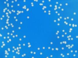 flocos de neve brancos espalhados sobre um fundo azul. lay flat simples com espaço de cópia. foto. foto