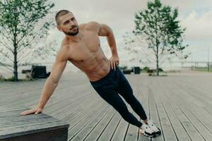 sem camisa barbudo homem lado prancha, resistência, Boa forma. ativo ao ar livre treinamento, roupa de esporte. foto