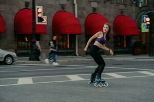 jovem esbelta e desportiva usa patins como meio de transporte na cidade gosta de passatempo favorito e melhora o humor vestido com roupas ativas poses na estrada exercícios regularmente mantém a forma perde peso foto