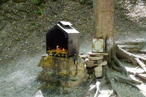 ortodoxo velas dentro a floresta debaixo uma árvore dentro uma caixa. a oração pedra de a estrada foto