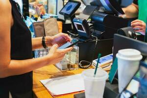 mulher digitalização qr código Forma de pagamento através da Móvel telefone às caixa dentro cafeteria. foto