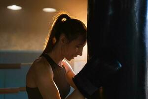 mulheres auto defesa menina poder. Forte mulher lutador em repouso depois de luta Treinamento em boxe anel. Forte menina cansado depois de soco boxe bolsa. Treinamento dia dentro academia. força em forma corpo exercite-se treinamento. foto