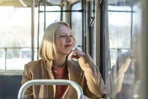 1 jovem mulher sorridente dentro uma ônibus enquanto olhando através a janela lindo jovem mulher levando ônibus para trabalhar. passageiro dentro a ônibus ou trem, tecnologia estilo de vida, transporte e viajando conceito. foto