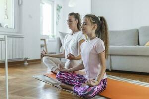 família mãe e criança filha estão acionado dentro fitness, ioga, exercício às lar. mãe e filha praticando ioga foto