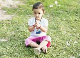 pequeno ásia menina praticando atenção meditação ao ar livre dentro uma parque. foto