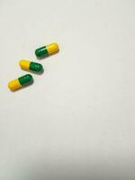 isolado branco foto do três remédio cápsulas verde e amarelo.