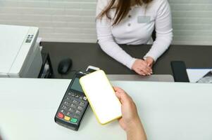 uma Smartphone com branco em branco digital scree sobre pos terminal ou crédito cartão leitor. sem dinheiro Forma de pagamento através da nfc tecnologia foto