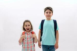 alegre escola crianças, criança menina e adolescente Garoto expressando positivo emoções, carregando mochilas, sorridente olhando às Câmera foto