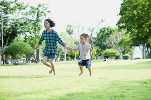 feliz sudeste ásia meninas jogando ao ar livre dentro a Primavera parque. ásia crianças jogando dentro a jardim verão período de férias. foto