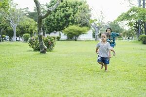 feliz sudeste ásia meninas jogando ao ar livre dentro a Primavera parque. ásia crianças jogando dentro a jardim verão período de férias. foto