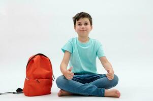 bonito adolescente escola Garoto dentro azul camiseta e jeans, com laranja mochila, manusear acima, sorridente, olhando às Câmera foto