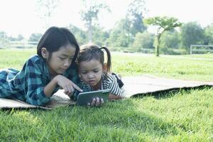 sudeste ásia meninas jogar Móvel telefones ao ar livre dentro a pátio durante a verão em período de férias. foto