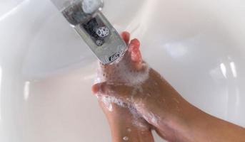 close-up de um homem lavando as mãos com sabonete na pia foto