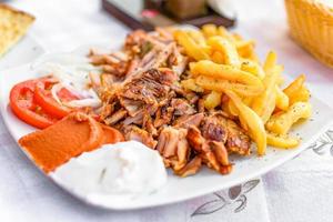 giroscópios gregos em um prato com batatas fritas e vegetais foto