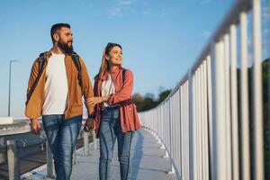 feliz casal segurando mãos e caminhando em pedestre passarela. turistas estão passeios turísticos dentro a cidade. foto