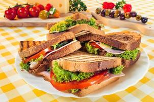 sanduíche club com presunto, salame, carne defumada, queijo, alface e rúcula. Preparação de sanduíche de torrada.
