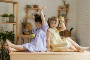 pequeno feliz meninas idiota por aí dentro a cozinha e comer maçãs foto