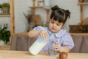 uma pequeno lindo menina dentro uma brilhante vestir é enganar por aí dentro a cozinha foto