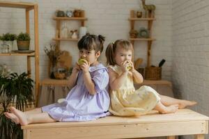 pequeno feliz meninas idiota por aí dentro a cozinha e comer maçãs foto